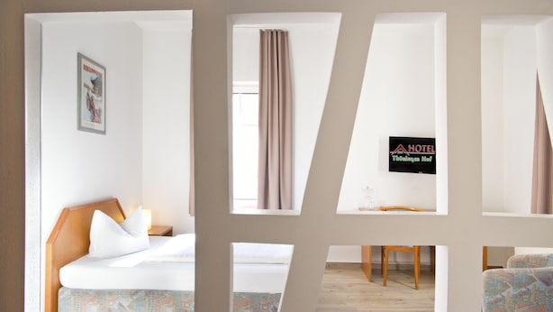 A hotel room with a bed, a nightstand, a chair, a table, and a window with curtains. - Hotel Thüringer Hof (Jena)