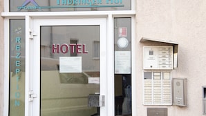 A hotel entrance with a reception desk, a sign indicating the hotel name, and a public telephone box. - Hotel Thüringer Hof (Jena)