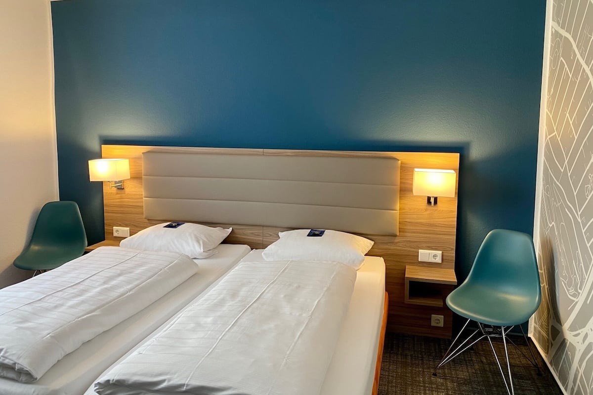 A hotel room with a large bed, two bedside tables, two lamps, and two chairs.