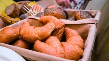 Verschiedene Backwaren, darunter Croissants und Brot, in einem Holzkorb präsentiert.