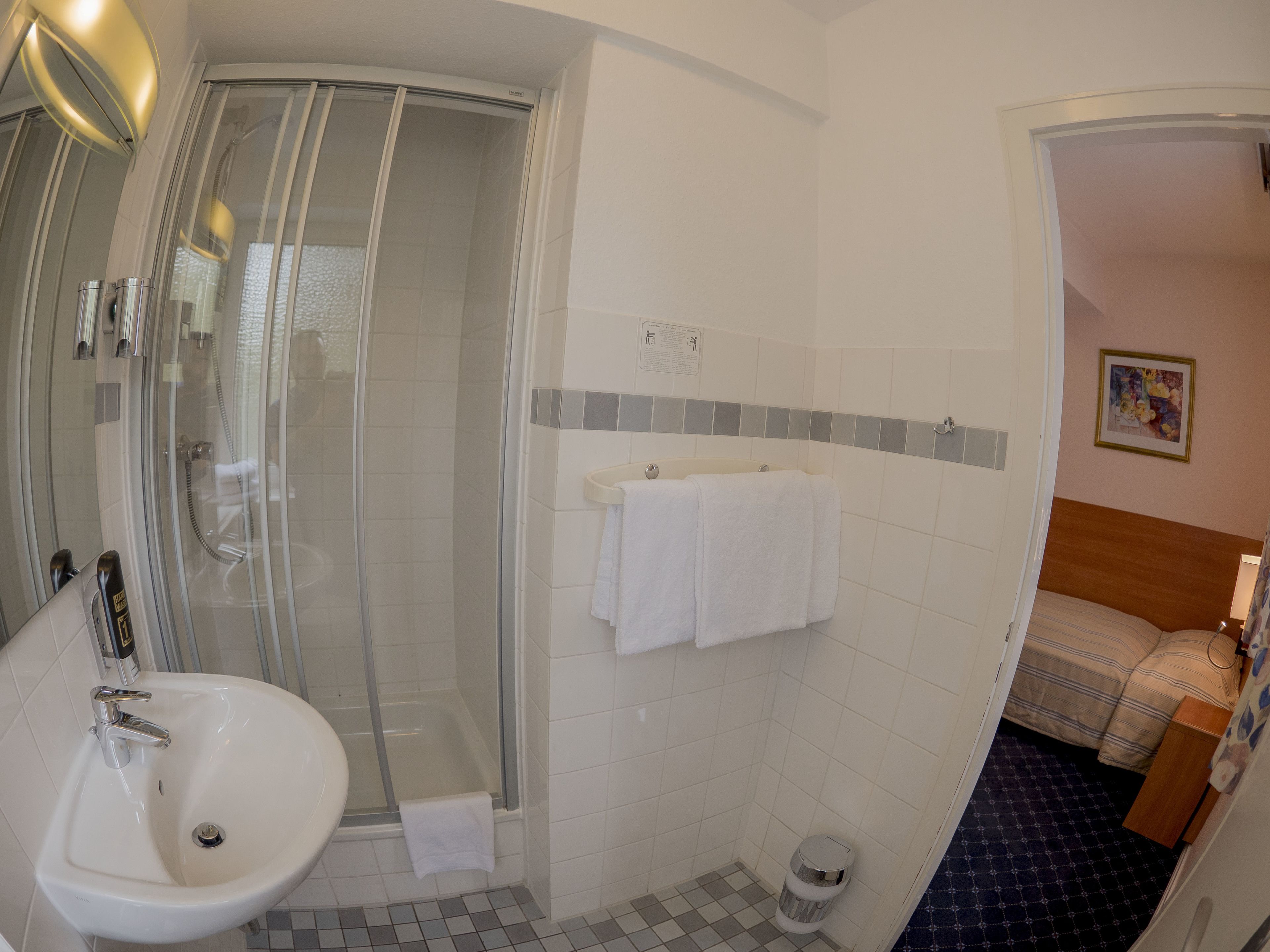 A bathroom with a glass-enclosed shower, a sink, and a small toilet.