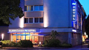 A hotel with a modern design, featuring a prominent neon sign and a visible entrance.