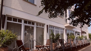 A row of white buildings with large windows and a balcony with wooden chairs. - Hotel Heide Residenz (Paderborn)
