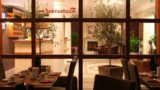 A hotel lobby with a reception desk, seating area, and a fireplace. - Hotel Heide Residenz (Paderborn)