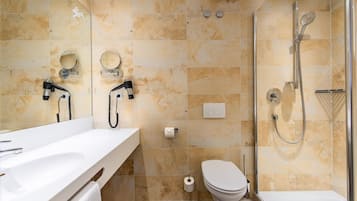 A bathroom with a shower, toilet, and two sinks with mirrors.