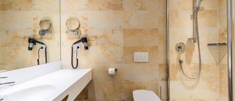 Une salle de bain avec douche, toilettes et deux lavabos avec miroirs.