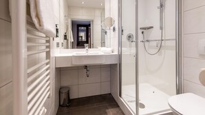 A modern bathroom with a glass-enclosed shower, a white sink, and a mirror. - Premier Inn Passau Weisser Hase (Passau)