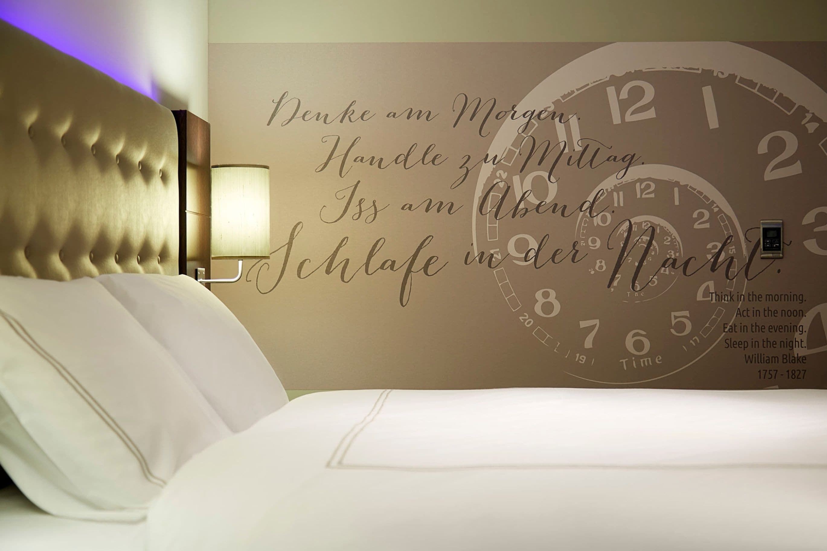 Een hotelkamer met een grote wandklok en een citaat van William Blake.