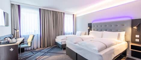 Una camera d'albergo con un letto, una scrivania, una sedia e un frigobar.