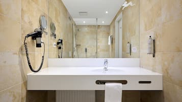 A bathroom with a white sink, a towel rack, a mirror, a hairdryer, and a bottle of hand soap.