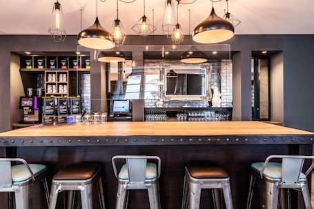 A bar area with stools, a counter, and a display of glasses.
