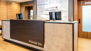 Una recepción de hotel con un cartel que dice 'Premier Inn' y una pared con frases motivacionales.