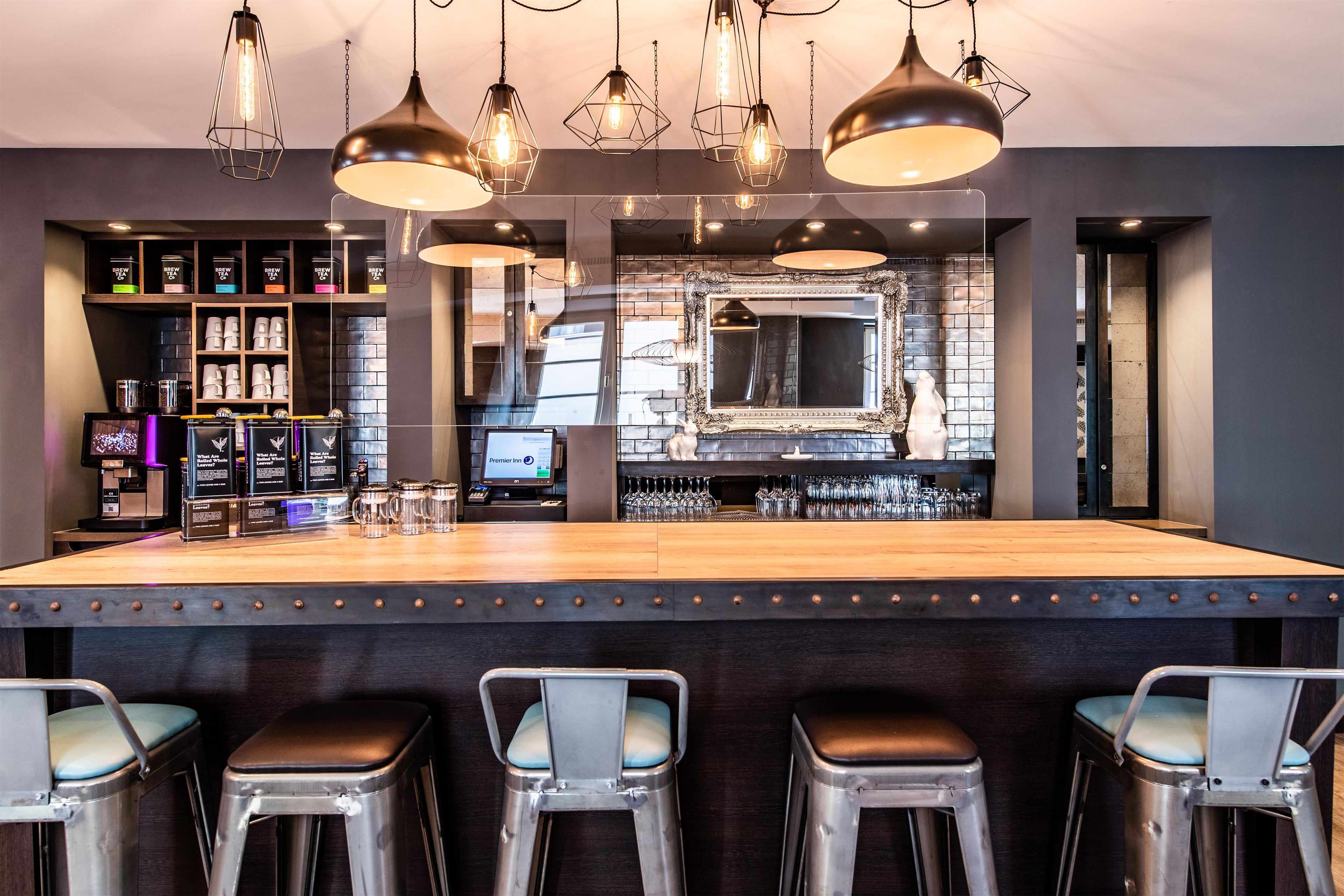 Un espace bar avec des tabourets, un comptoir et un présentoir à verres.