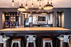 A bar area with stools, a counter, and a display of glasses.