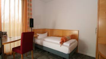 A hotel room with a single bed, a desk, a chair, and a wardrobe.
