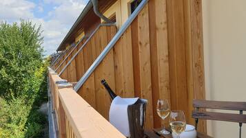 A wooden deck with a table set for two, a bottle of wine, and glasses.