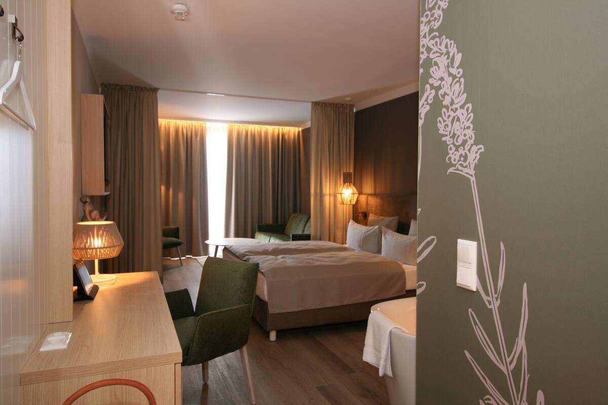 A hotel room with a bed, a desk, a chair, and a lamp.
