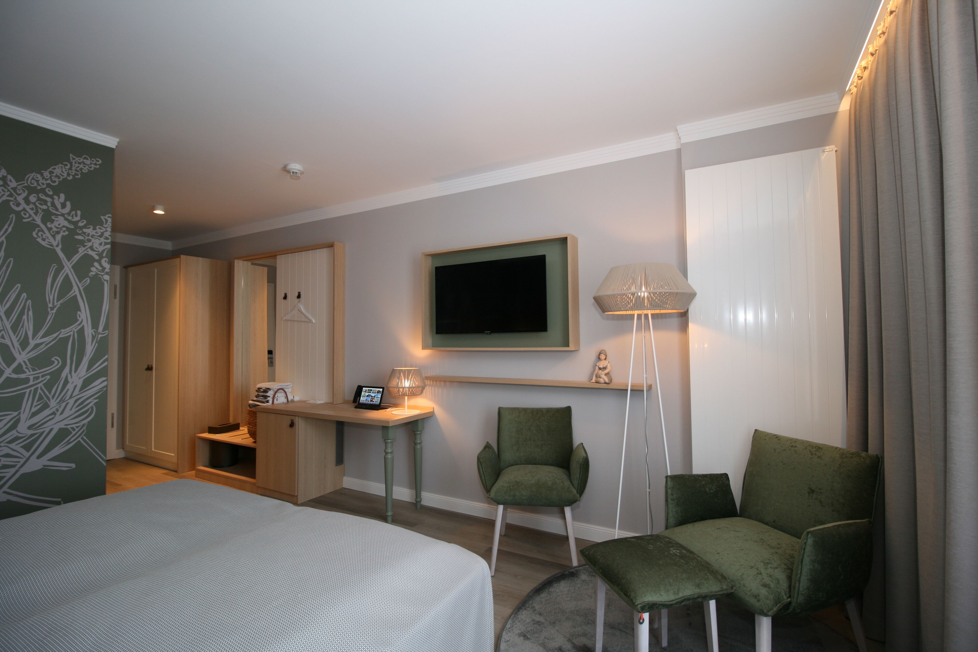 A hotel room with a bed, a desk, a chair, a TV, and a lamp.