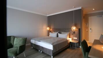 Un dormitorio moderno con una cama grande, lámparas de noche, una silla verde y una mesa de madera.