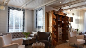 A living room with a sofa, armchairs, a wooden cabinet, and a lamp. - Hotel Rittmeister (Rostock)