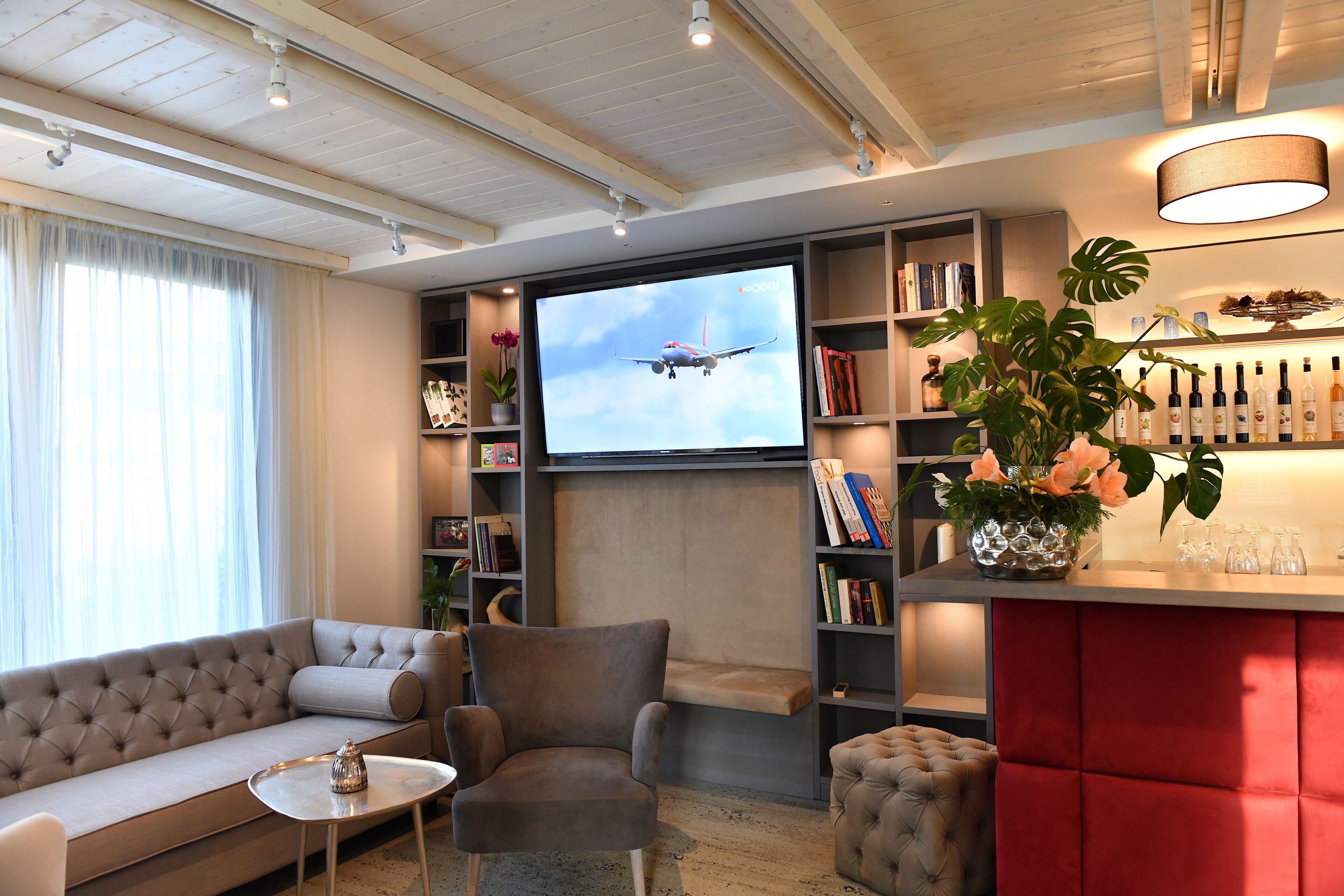 Un salon moderne comprenant un grand téléviseur à écran plat, un canapé, un fauteuil, une petite table et une bibliothèque.