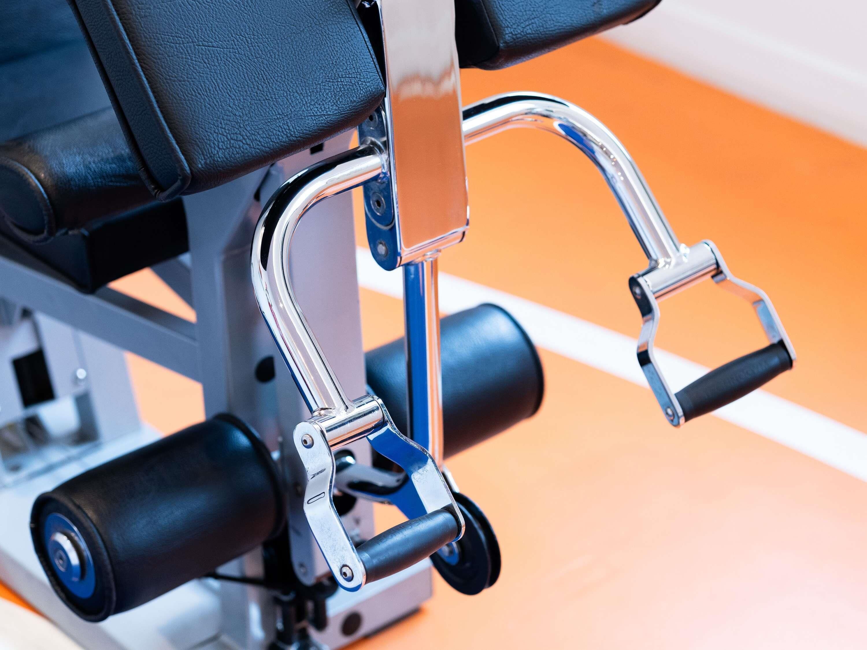 A close-up of a gym machine with a black seat and metallic components.