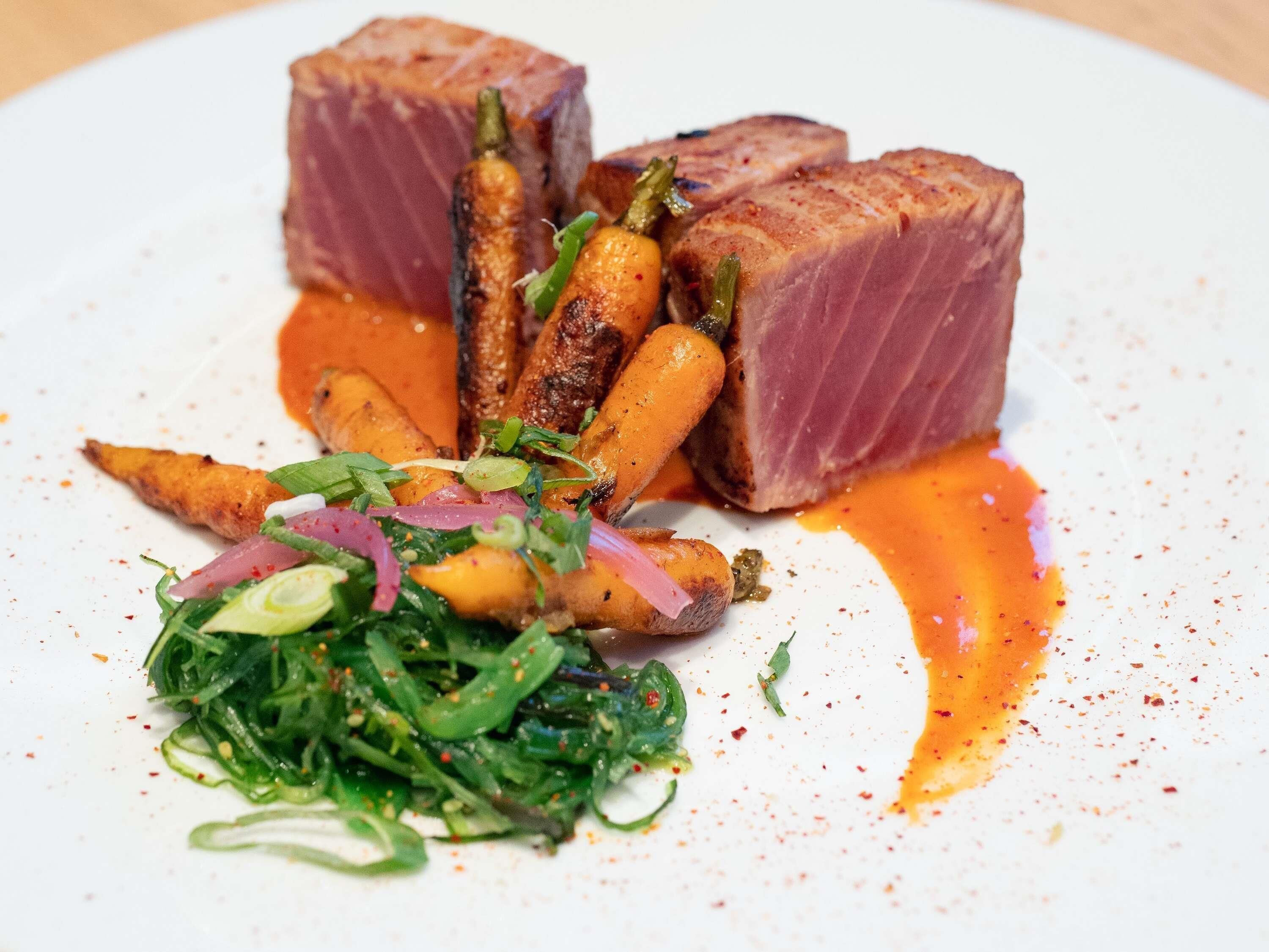 Prato de comida com carne, cenouras e vegetais verdes.