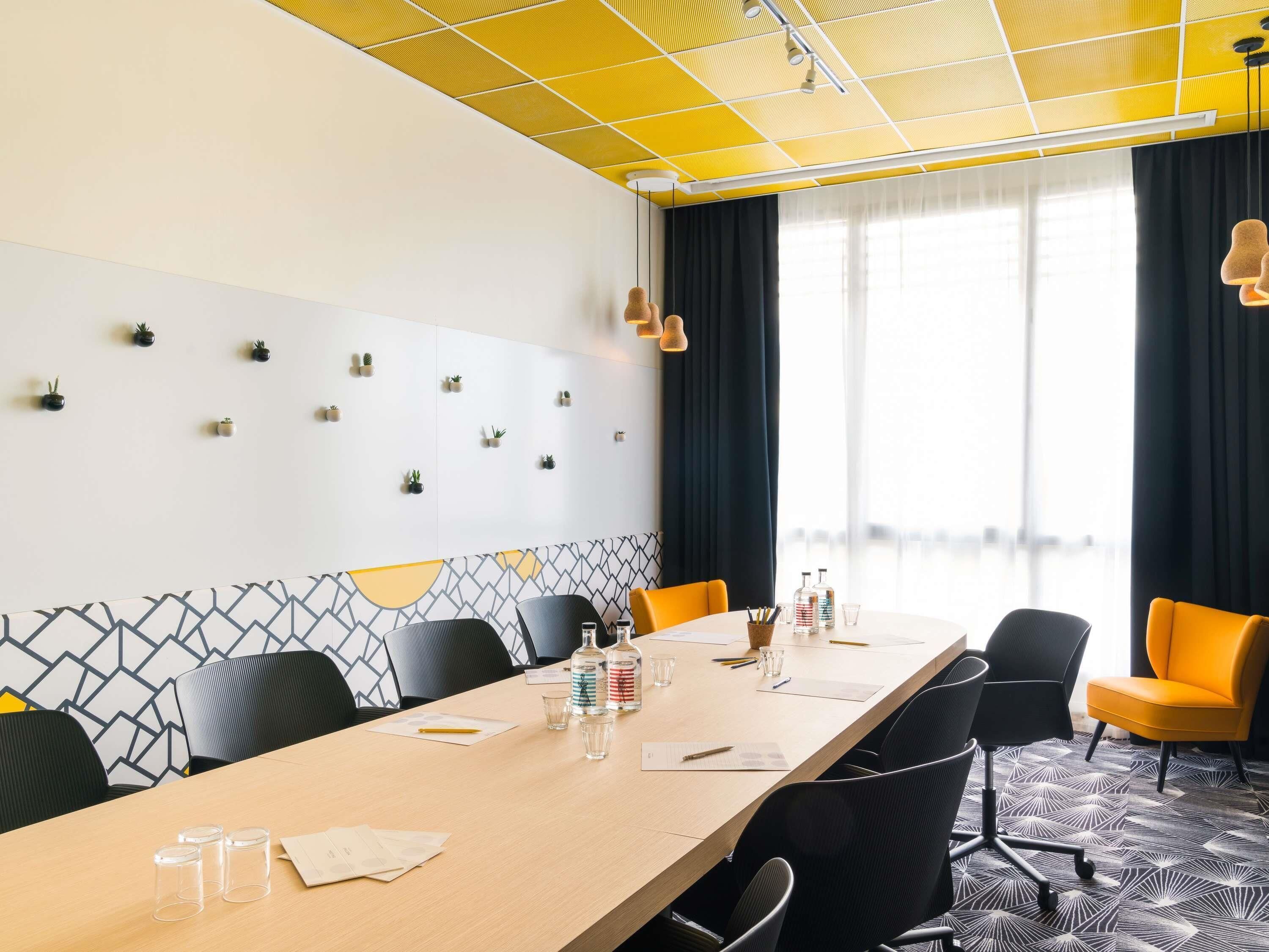 A conference room with a long table, chairs, and a patterned wall.