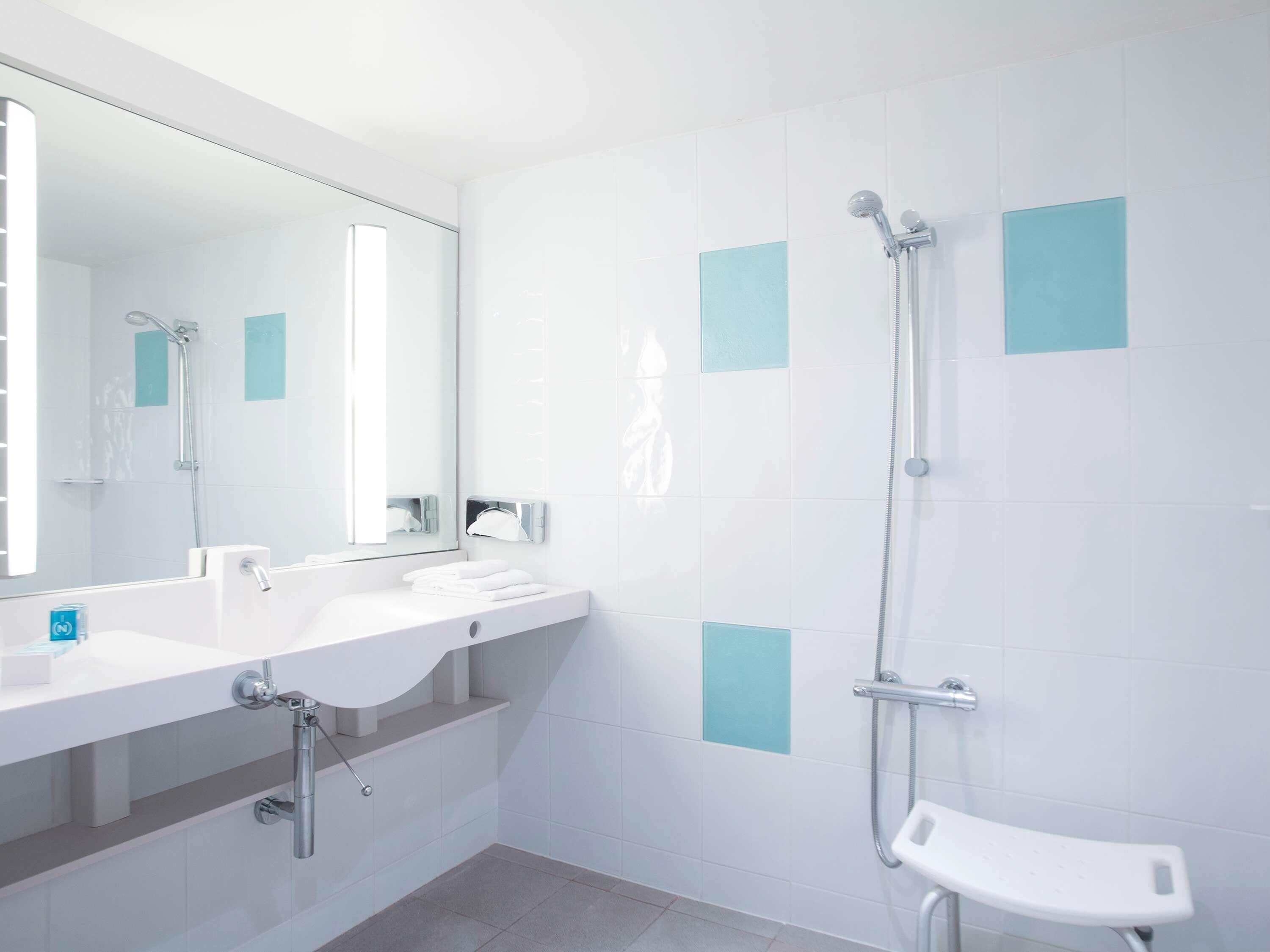 A modern bathroom with a white sink, mirror, and shower.