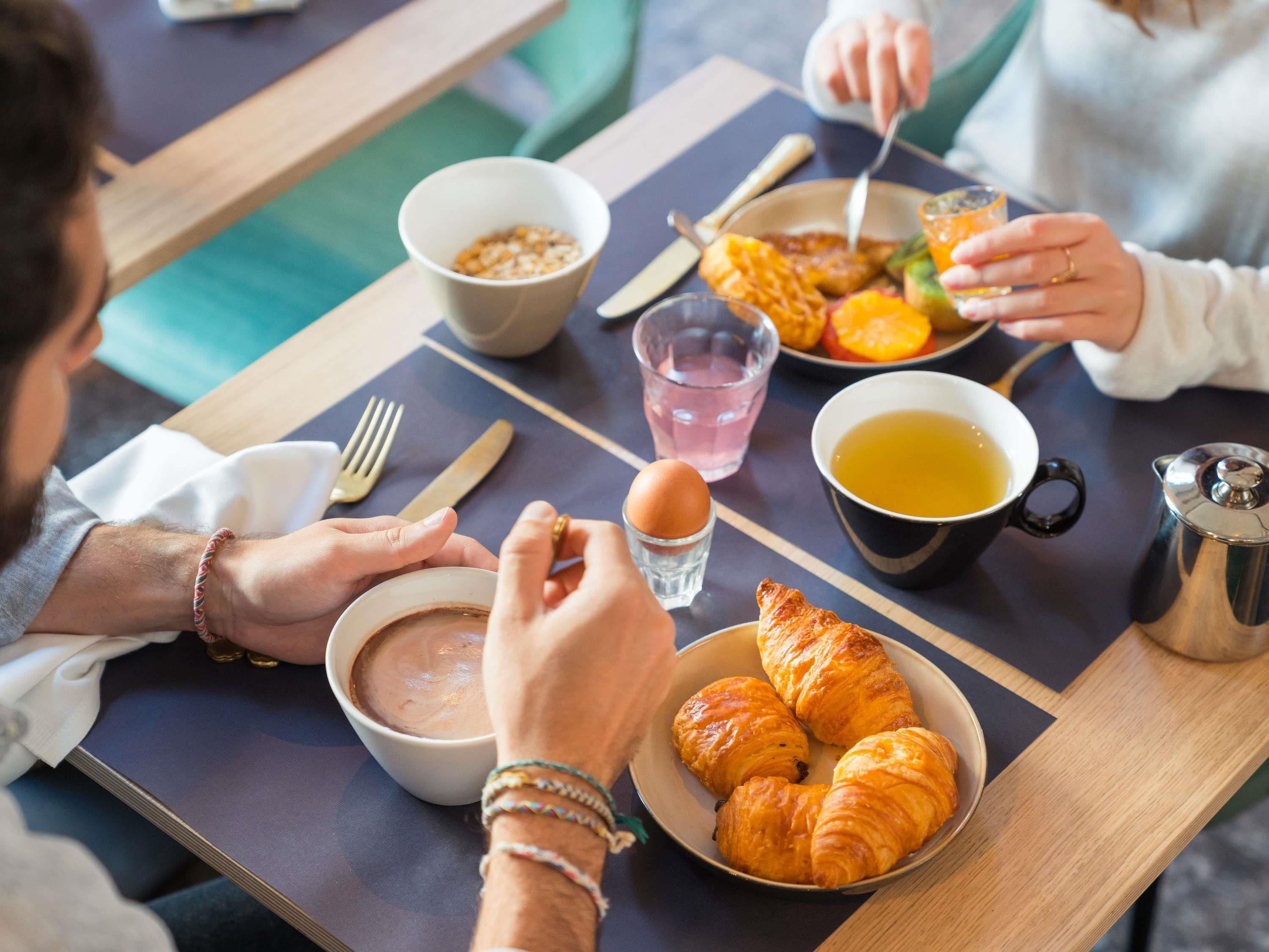 Un desayuno con cruasanes, un tazón de sopa, una taza de té y una fuente de fruta.