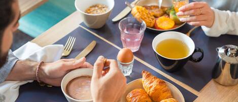Un desayuno con cruasanes, un tazón de sopa, una taza de té y una fuente de fruta.