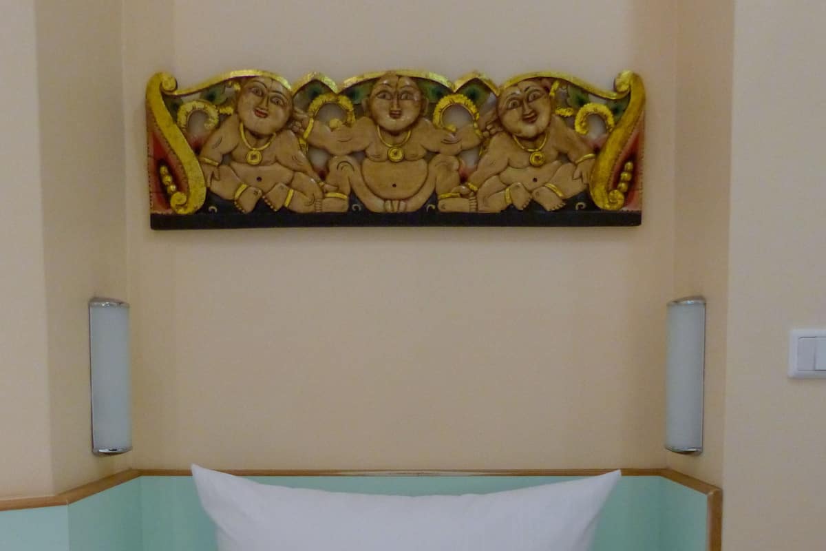 A bed with a white mattress and a headboard with a decorative panel above it.