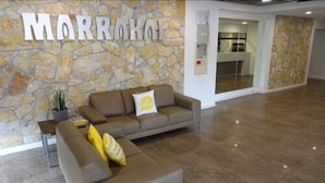 A reception area with a stone wall and a large sign reading "MARRAKOI". - Marrakai Apartments (Darwin)