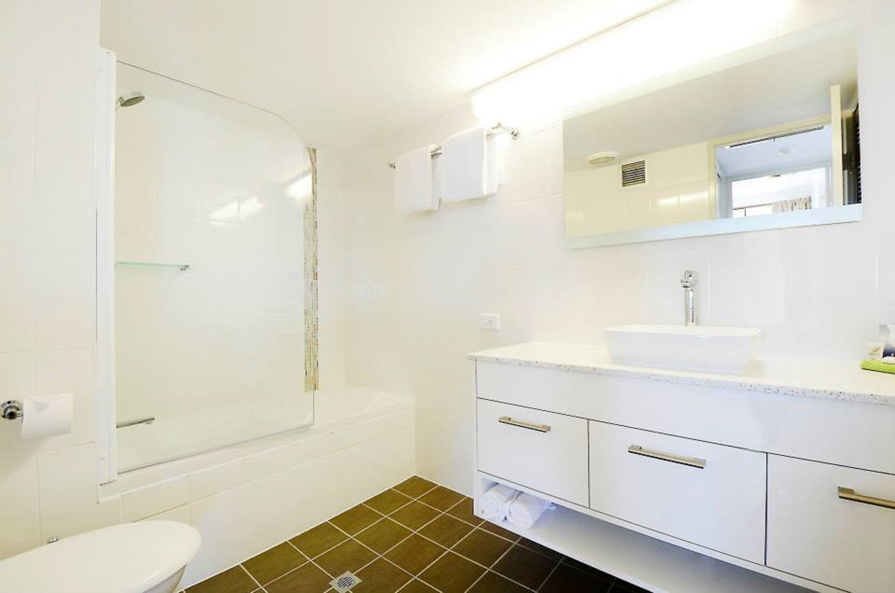 A bathroom with a glass shower enclosure, a white sink, and a mirror above the vanity.