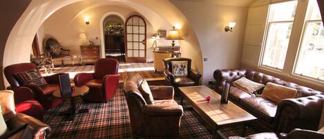 A cozy living room with a checkered floor, leather sofas, and a fireplace.