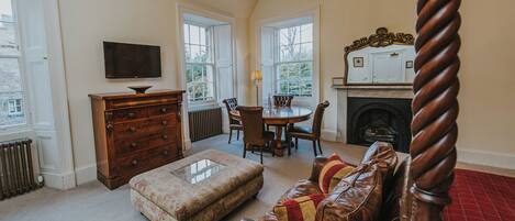 A traditional room with a fireplace, a dining table, and a television.