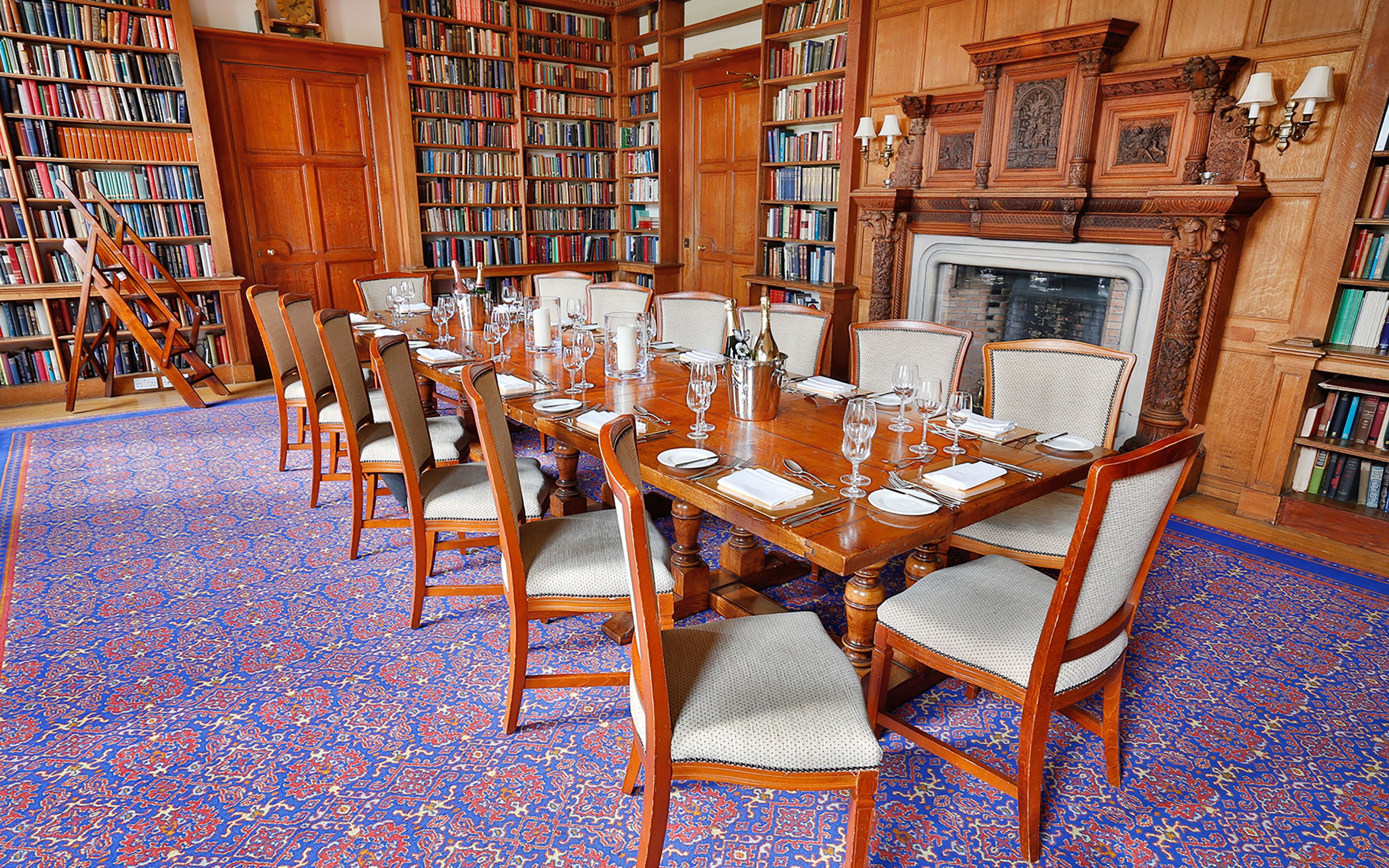 Une salle à manger élégante, avec une longue table en bois dressée pour un repas, entourée de chaises dotées d’assises rembourrées.