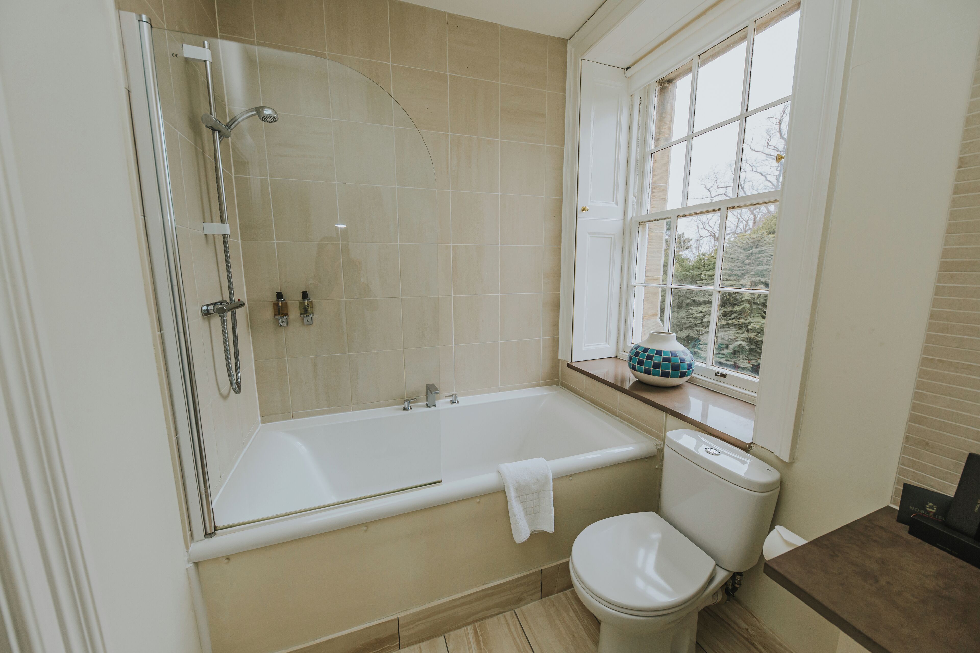 Une salle de bain avec une baignoire, des toilettes et une fenêtre donnant sur un beau paysage.