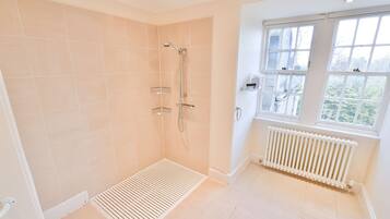 A modern bathroom with a shower, a window, and a radiator.