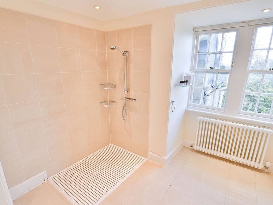 A modern bathroom with a shower, a window, and a radiator.