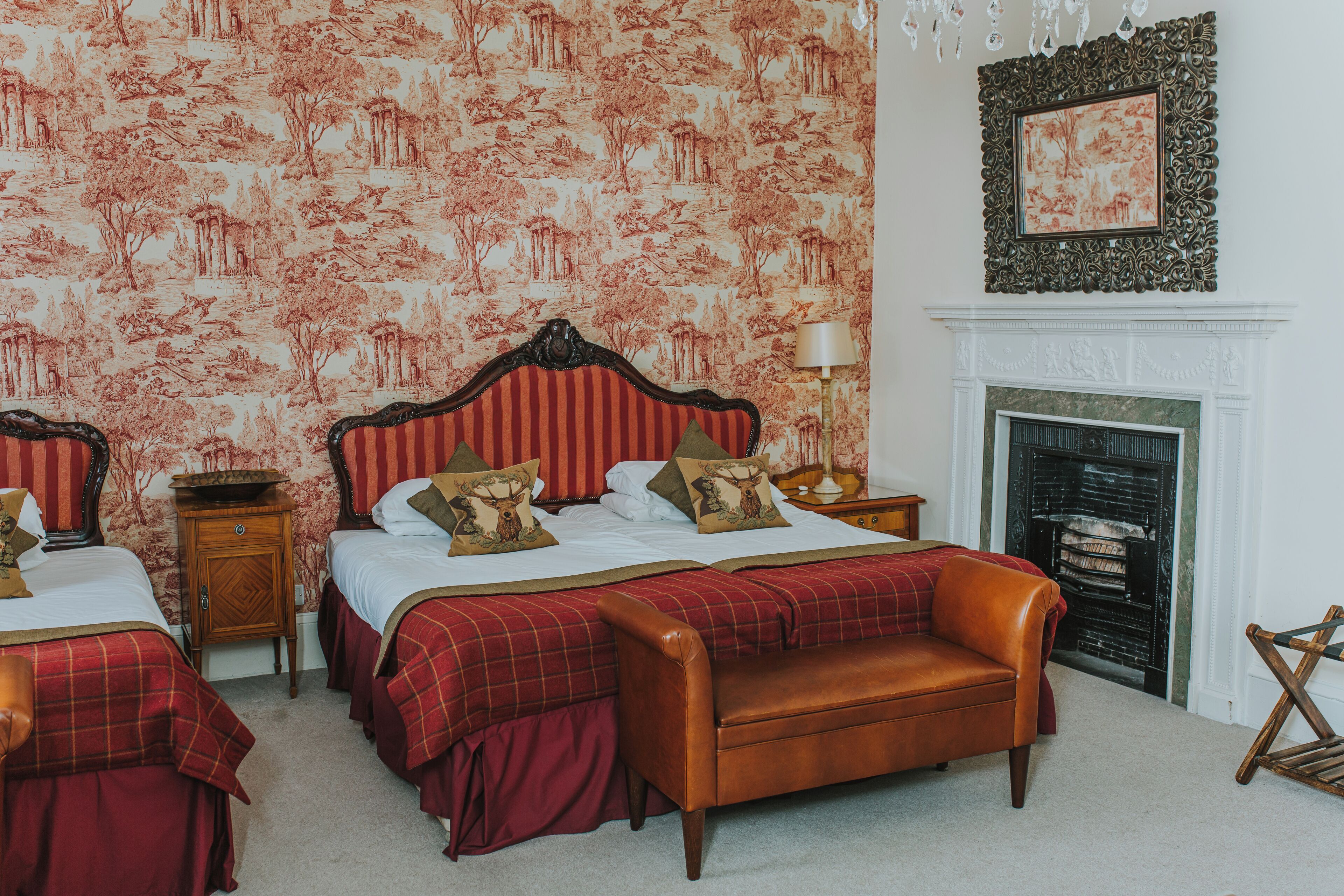 Quarto com duas camas, lareira e um candelabro.