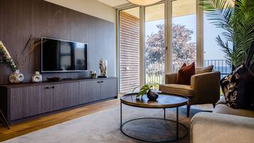A modern living room with a flat-screen TV, dark wood cabinetry, a round coffee table, and a sofa with cushions.