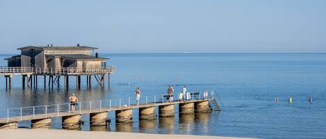 A pier extending into calm waters with a building on one end.