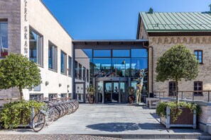 Un edificio con recepción, entrada de vidrio y una fila de bicicletas estacionadas afuera.