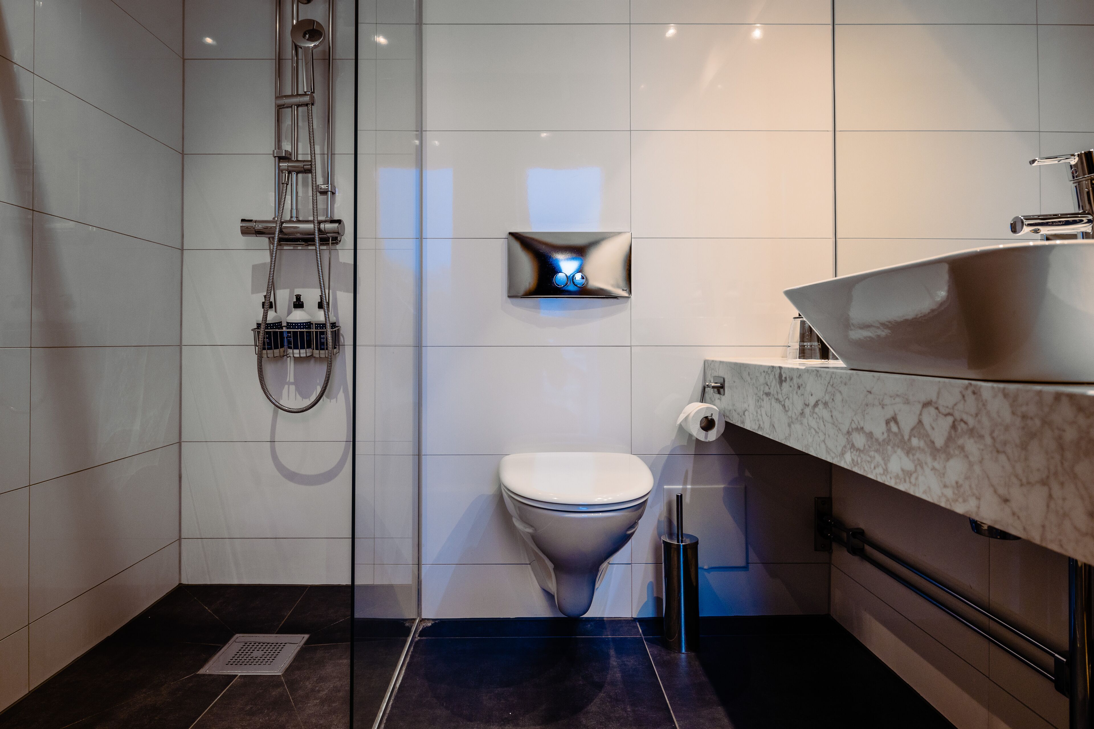Un bagno moderno con doccia vetro, servizi igienici e lavandino in marmo.