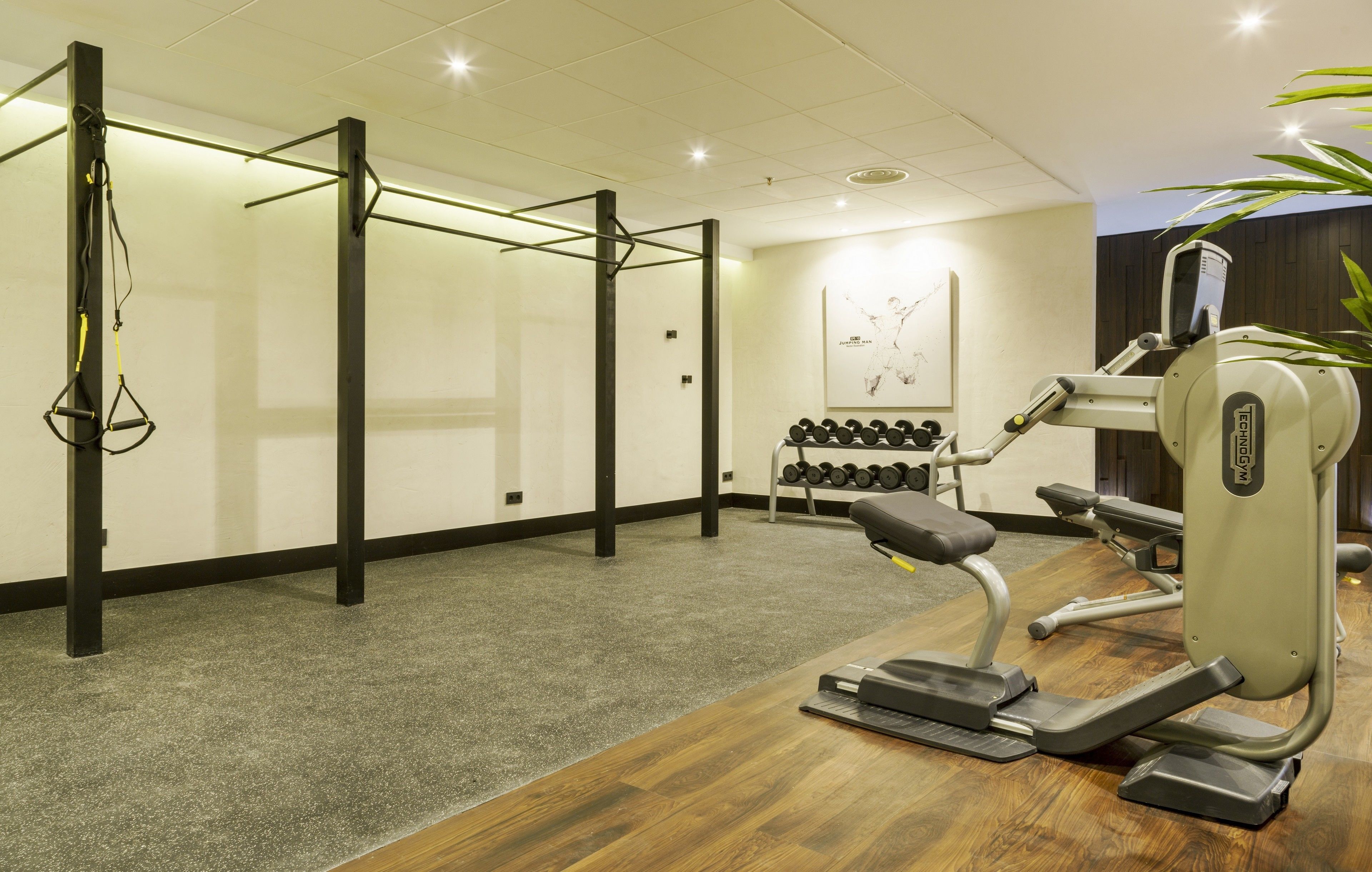Un gimnasio con equipo de ejercicio, incluyendo una barra de dominadas, mancuernas y una bicicleta estática.