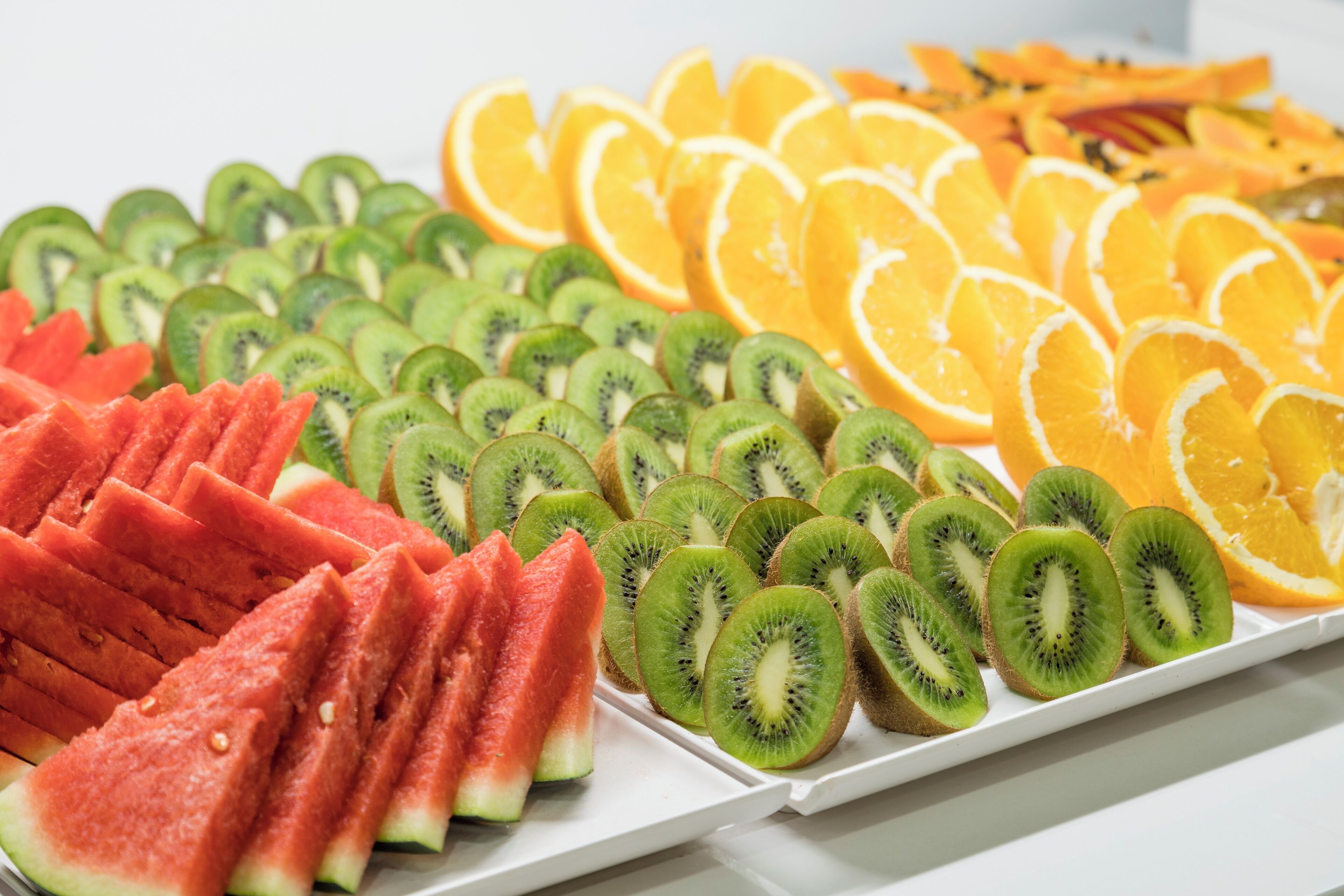 A tray of sliced fruits including watermelon, kiwi, and orange.
