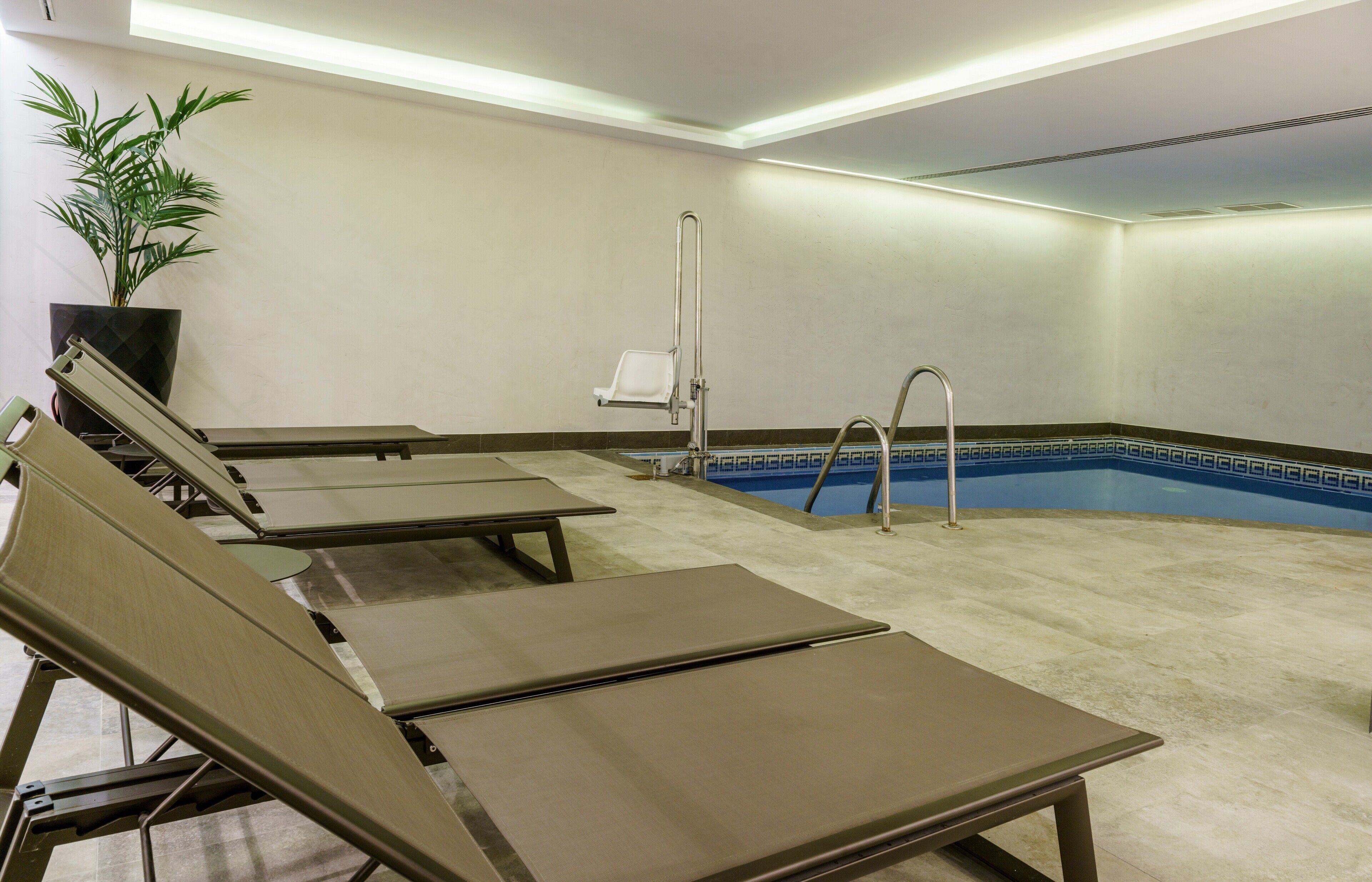 Un espace piscine aménagé avec des chaises longues et un élément décoratif aquatique.