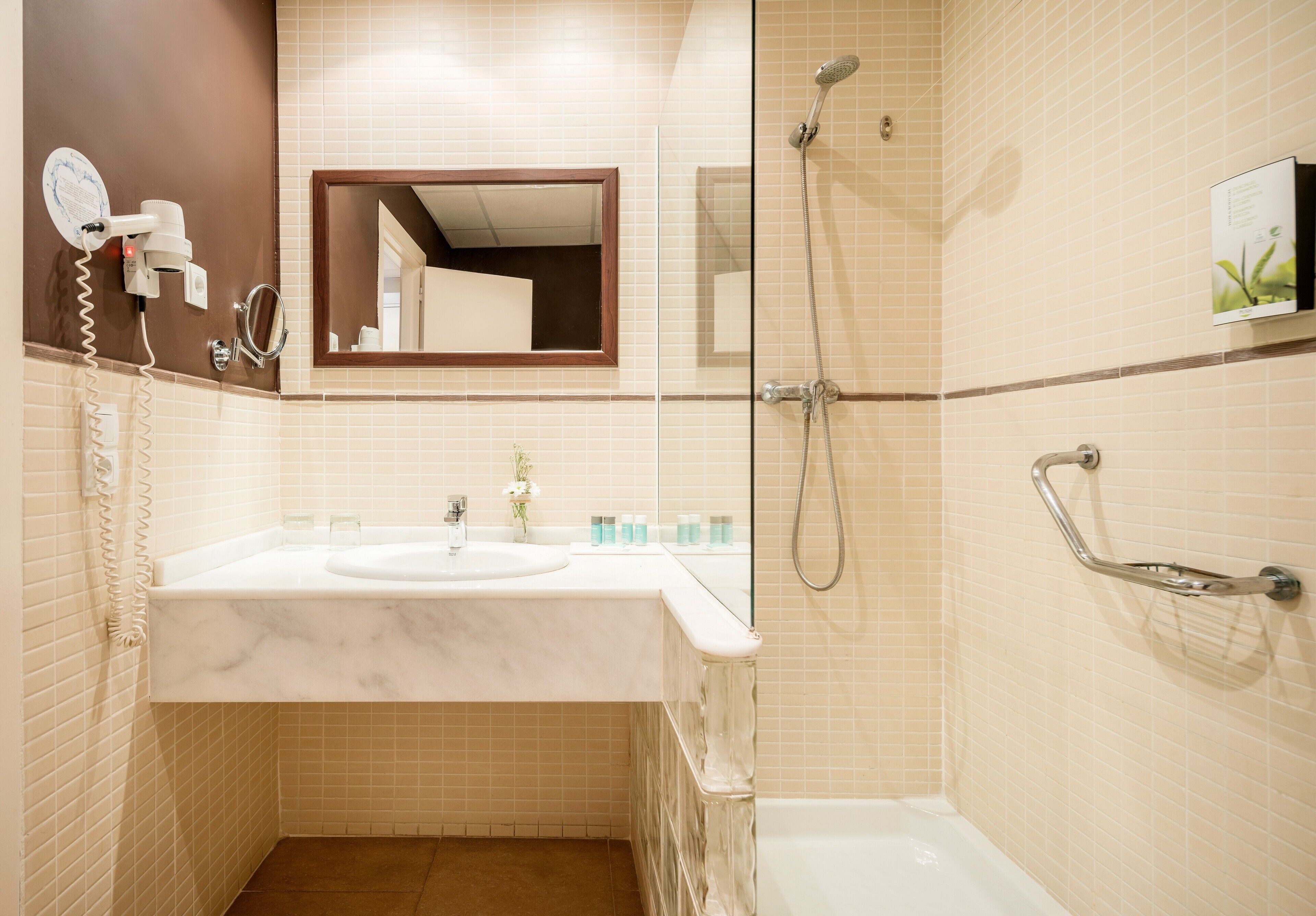 Un baño con lavamanos de mármol, ducha de mano, espejo de mano y toallero.