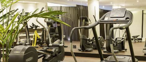 A gym with various exercise machines, including treadmills and weight machines, and a mirror reflecting the equipment.